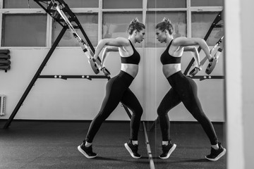 Sporty woman doing TRX exercises in the gym