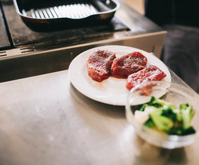 raw beef steaks before cooking lies on a white plate among vegetables - 193348035