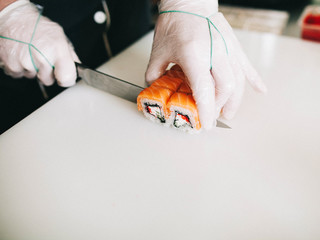 Men's hands prepare Japanese sushi rolls, cut them - 193348070