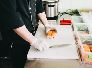 Men's hands prepare Japanese sushi rolls, cut them - 193348074