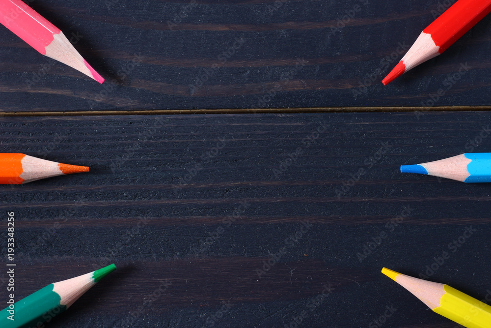 Poster colored pencils on a dark background with an empty space