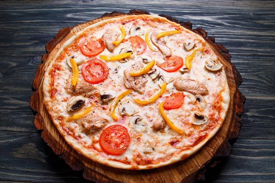Appetizing pizza with tomato, chicken, paprika and mushrooms, close up. Italian food, restaurant menu photo