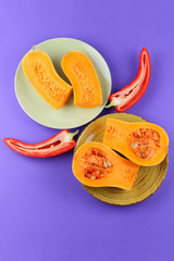 Halves of a pumpkin and red pepper on a green plate, pumpkin on a purple background, vegetables pop art, minimalism, orange and red vegetables on a purple background, Bulgarian pepper, pumpkin for a d