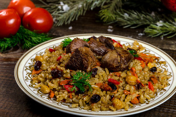 Uzbek national dish pilaf on a dark wooden background with pickles