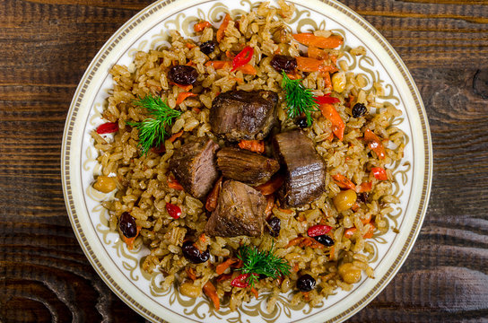 Uzbek national pilaf dish on a dark wooden background