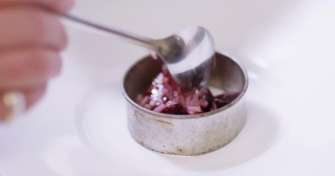 4K Close up on hands, unrecognizable chef preparing gourmet starter dish & spooning it into a mould. Could be restaurant, hotel or domestic kitchen.