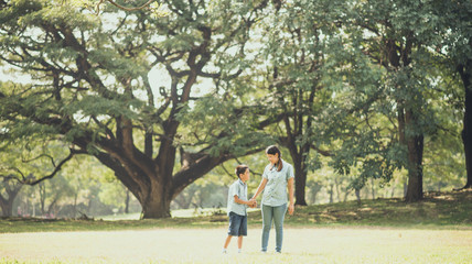Obraz premium Little boy walking with mother in the park