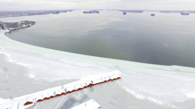 Freezing lake landscape with row of red boathouses