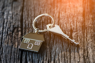 keychain with house symbol, key on wooden background. home loan concept.