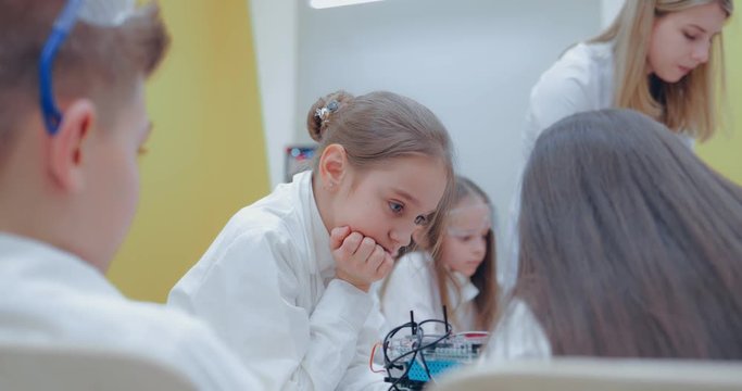 Cute childrens drawing something on paper with 3d pen while learning how to use new gadget