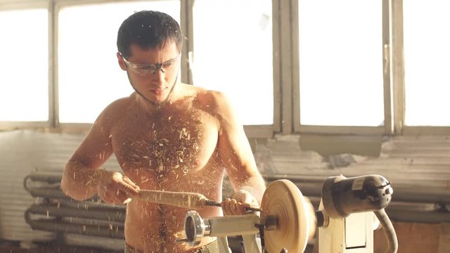 Naked Man Carpentering in Workshop and Using Small Manual Lathe.