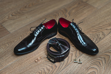 Brown bow tie lies on a belt, leather shoes. Grooms wedding morning