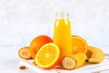 Obraz na płótnie Canvas Orange smoothies from orange, banana on a gray concrete table.