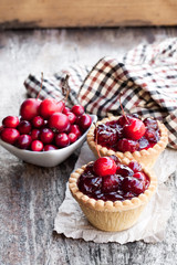 egg  custard tarts with cranberry jam and wild apples on wooden table