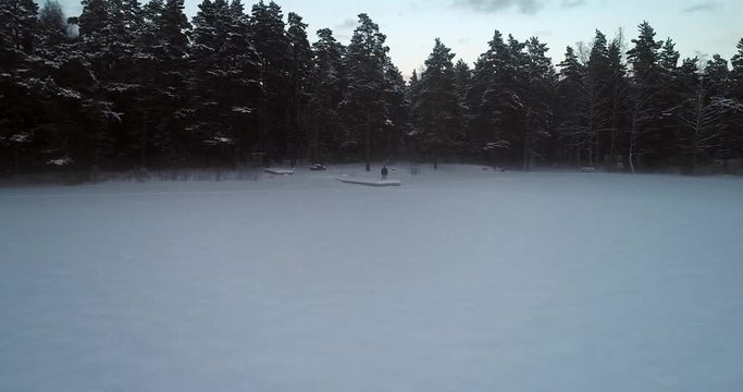 Man standing at a wharf, Cinema 4k view over a hiker on a dock, on a frozen smokey, winter lake, on a cold winter day, in Uusimaa, Finland