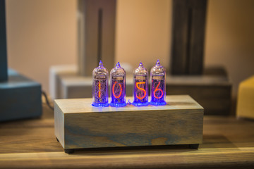 Desktop clock hands. Wooden clock with numbers. Discharge lamps in a transparent enclosure made of plexiglass. Numbers like an edison bulb