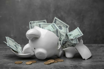 Broken piggy bank with money on table