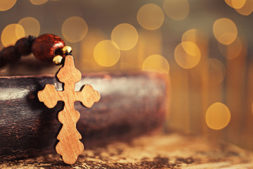 Wooden cross and book against defocused lights