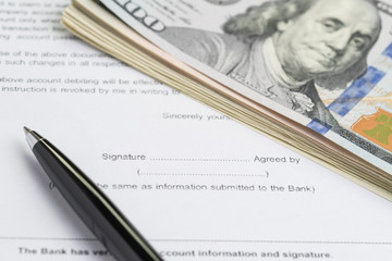 Printed paper form with pen to sign and US Dollar banknotes as financial money loan, mortgage or buy and sell contract with bank