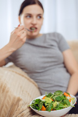 Obraz na płótnie Canvas A beautiful girl eating healthy food. Focus on vegetarian salad