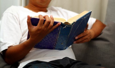 Man reading book while sitting on sofa
