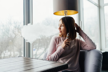 Portrait of cute young vaping girl. Vapor concept. Vaping e-Cigarette