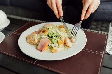 Woman hands ready to eating Caesar salad and drinking tea in the restaurant