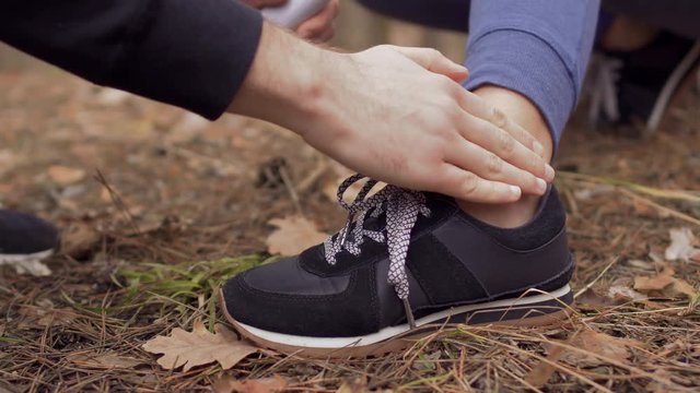 Man applies cream on injury of ankle to a woman