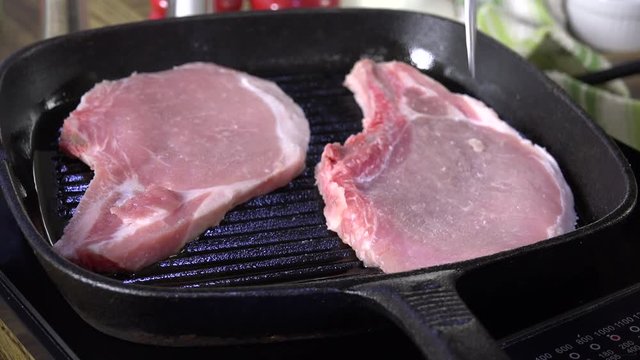 Putting pork chops on a cast iron grill