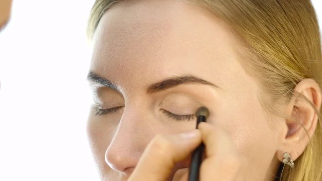 Close-up of professional make-up artist doing everyday makeup, puts powder on womans cheeks with brush
