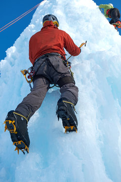 Alpinist man with ice tools axe climbing a large wall of ice. Outdoor portrait