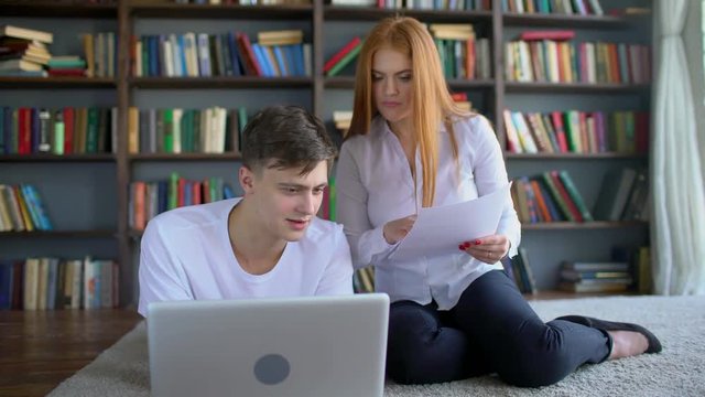 Male and female students learning and Using Laptop in the library. Two students brainstorming work by discuss with desktop in trendy loft close up with background books. High school friends meeting in