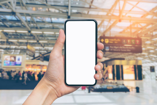 Man's hand shows mobile smartphone with white screen in vertical position, Blurred or Defocus image of international airport for use as Background vintage tone. - mockup template and clipping path