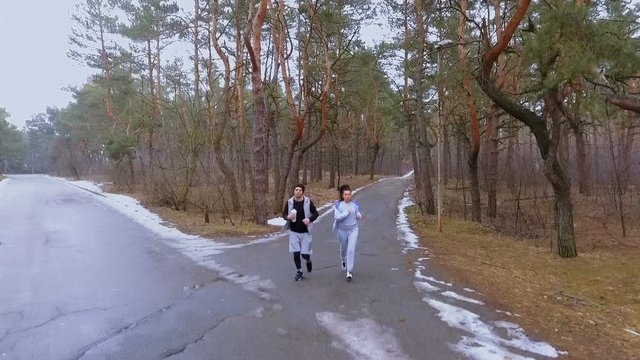 Two friends makes jogging in the morning in winter forest