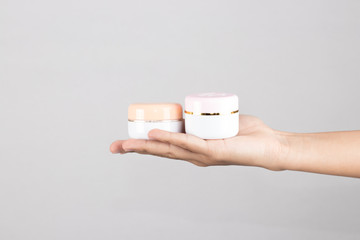 Cream jar in hand isolated on white background