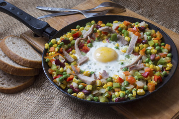hot breakfast of fresh sliced vegetables in a frying pan with fried egg
