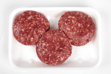 Tray with raw beef burgers isolated on white background