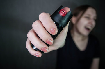 Self-defense concept: a young girl defends herself with a gas bottle pepper spray