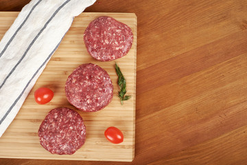 Raw cutlet of minced meat on a wooden cutting board.