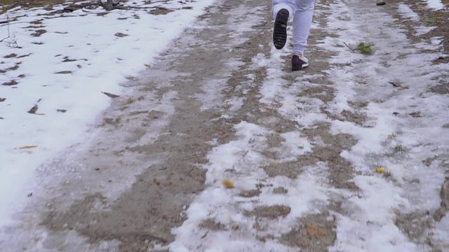 Young woman in snickers runs on snow road in slowmotion