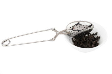 Black tea, and tea strainer with chain, isolated on a white background.
