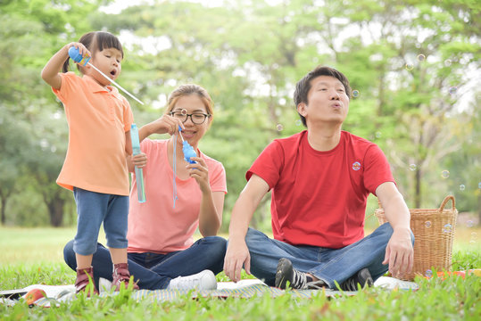 Asian family are blowing soap bubbles together.