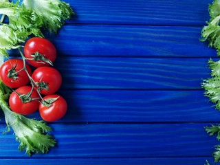 помидоры черри и зеленый салат на синем деревянном фоне