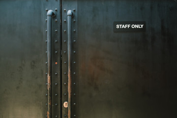 "Staff Only" door on the grey brick wall background.