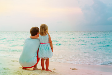 father and little daughter hug on beach