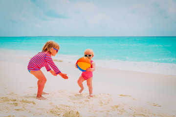 cute little girls playing ball on beach