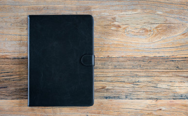 Leather case for tablet computer on wood background.
