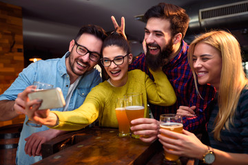 Group of young friends in bar drinking beer having fun