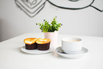 dessert and coffee at cafe with plastic plant in the vase on white table. subject is blurred.