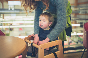 Young mother putting child in seat